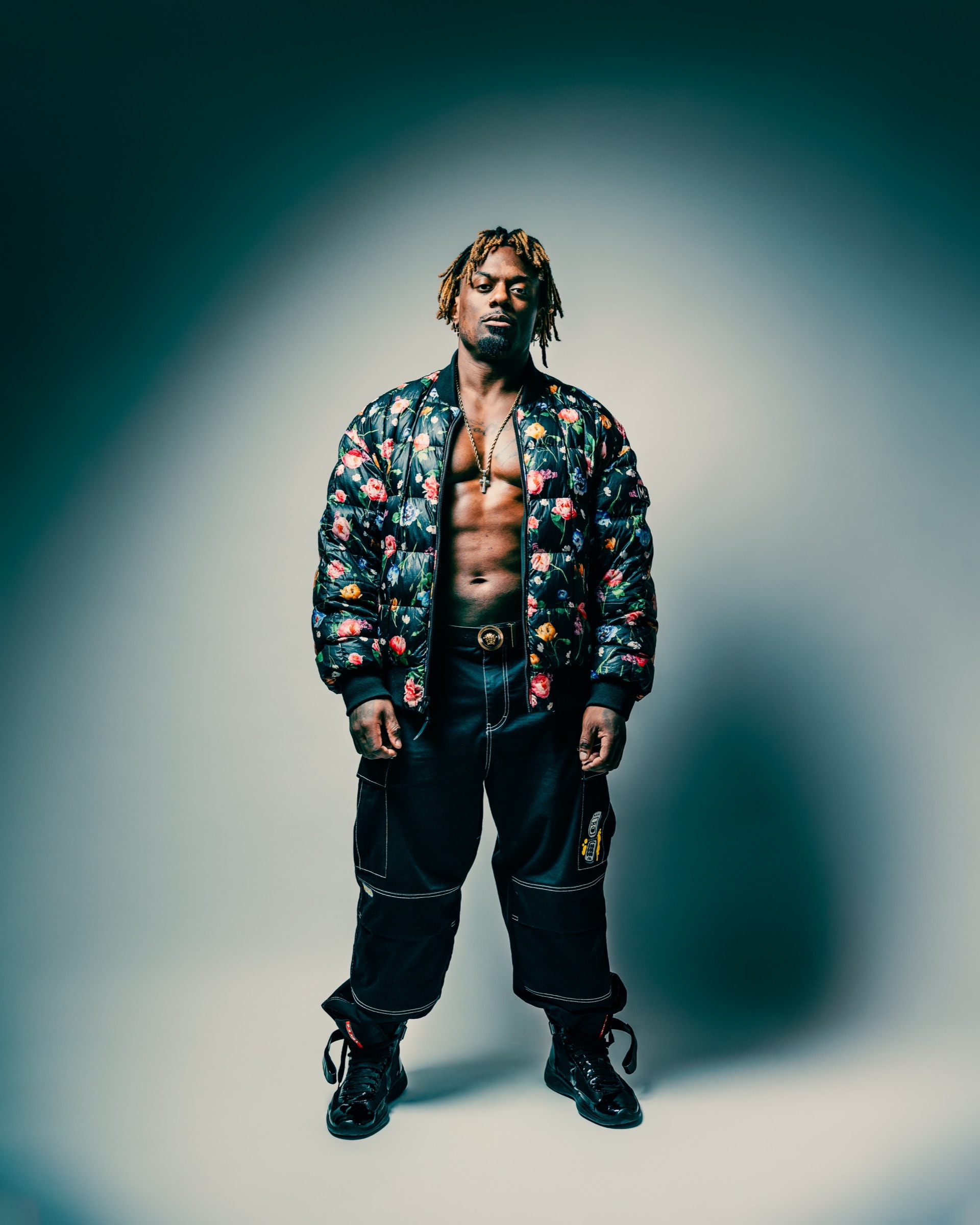 Dat Boi Jonni full body studio portrait, floral bomber jacket open, athletic physique, direct gaze, dramatic editorial lighting