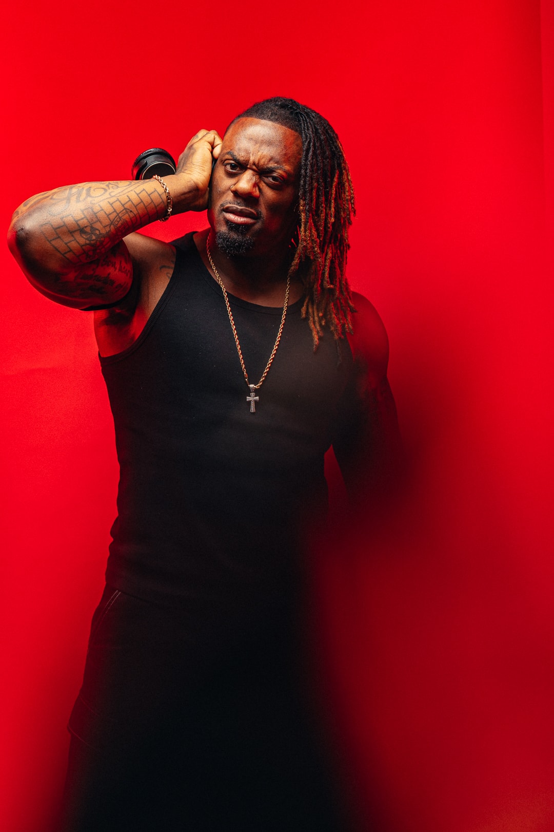 Dat Boi Jonni studio portrait on red background, hand to headphones