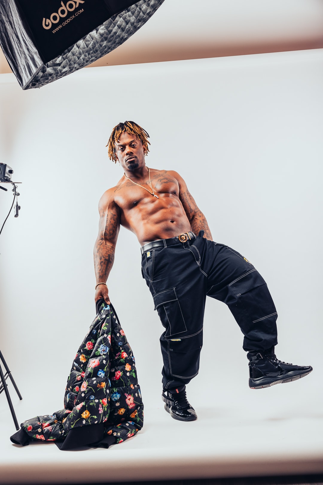 Dat Boi Jonni studio portrait, floral jacket draped over arm, shirtless