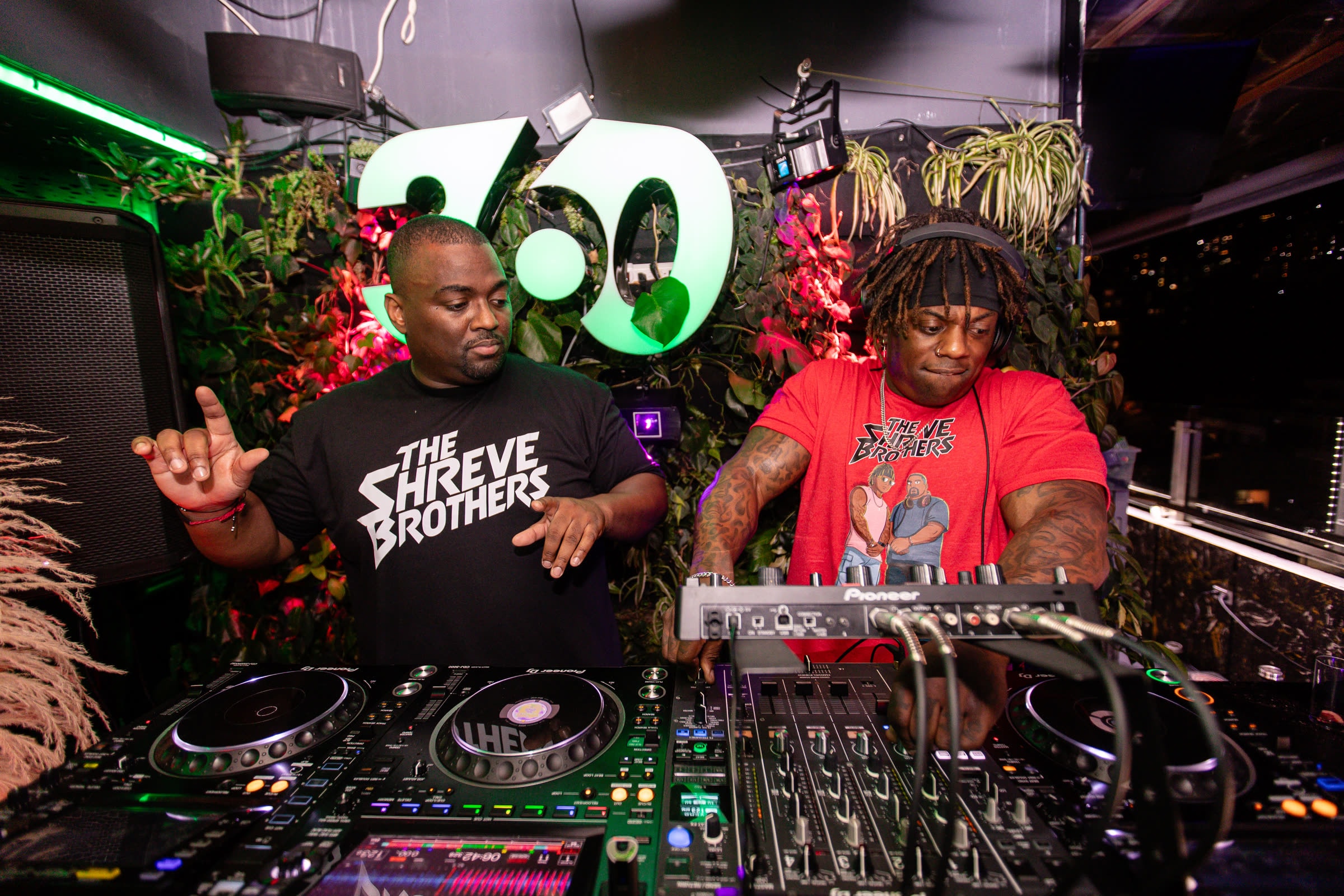 The Shreve Brothers behind the decks together, matching Shreve Brothers tees, tropical stage backdrop